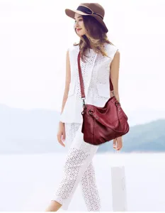 Detailed view of women's vintage wine red leather crossbody hobo shoulder bag lifestyle shot.