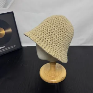 Gedetailleerd close-up van de beige gebreide bucket hat met fijne gehaakte textuur.