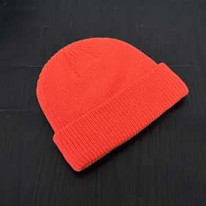 Orange knit beanie detail shot, stylish winter cold hat, comfortable short skull cap.