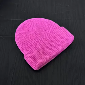Bright pink knitted beanie close-up, ribbed texture winter skull cap detail display.