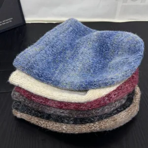 Close-up detail shot of colorful slouchy knit beanies stacked neatly, warm winter hat collection.