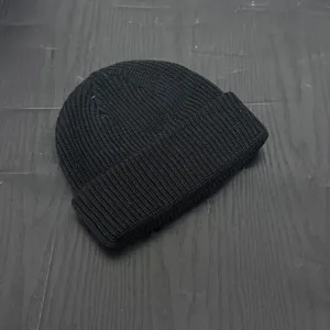Close-up shot of a black knitted beanie cap, showing fine texture and simple modern style.