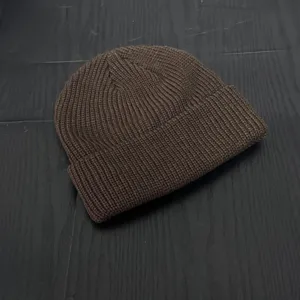 Dark brown knitted beanie hat, close-up view of textured rib knit style for cold weather wear.