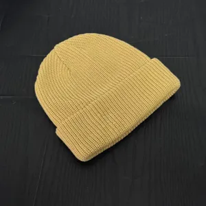 Yellow knitted beanie detail shot, textured wool skull cap close-up, stylish streetwear.