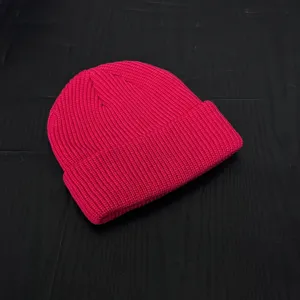 Detailed shot of a bright pink cuffed knit beanie, soft texture and cozy winter accessory.
