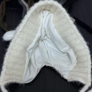 Detailed view of the cute white knitted bear ear hat interior lining, warm winter fleece inside.