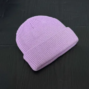 Detail view of a light purple knitted beanie, short dome winter skull cap with turn-up cuff.