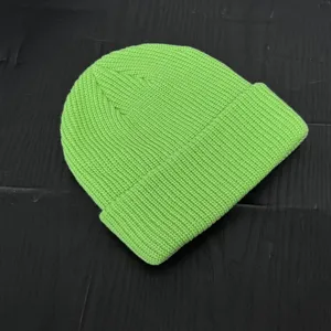 Close-up of a vibrant neon green knitted beanie showing detailed knit texture and fabric quality.