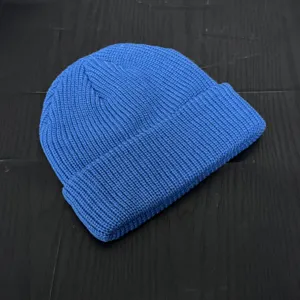 Close-up detail of a classic blue knitted beanie, showcasing fine rib knit texture and quality.