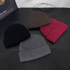 Detailed view of trendy knitted beanies in four colors, short dome style for winter wear.