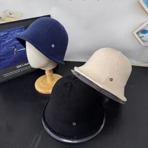 Λεπτομερής προβολή πλεκτών καπέλων bucket φθινοπώρου χειμώνα σε μπλε, μπεζ και μαύρο μέταλλο.