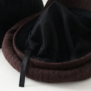 Nahaufnahme der braunen Strickbarette Textur, zeigt weiches Zopfmuster und Innenfutter.