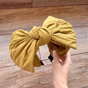 Détail serre-tête large avec nœud jaune moutarde, accessoire cheveux stylé en tissu.