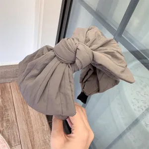 Gros-plan sur le serre-tête en tissu gris avec grand nœud, mettant en valeur le nœud texturé.