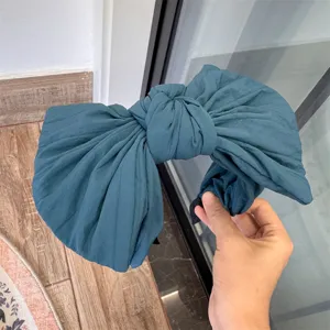 Gros plan détail du grand serre-tête nœud vert foncé, cerceau de cheveux uni large et élégant.