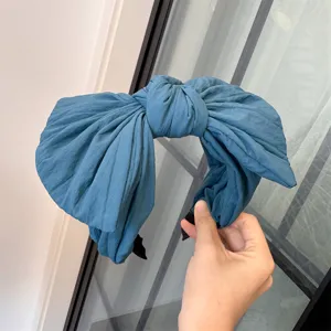 Gros plan détaillé du serre-tête nœud surdimensionné bleu, montrant sa texture en tissu froissé.