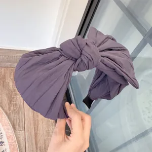 Gros plan détaillé du serre-tête nœud plissé gris foncé, mettant en valeur sa texture.