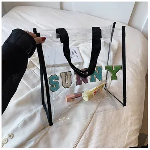 Transparente PVC Tragetasche Detailansicht mit bunten Buchstabenstickereien und schwarzen Henkeln.