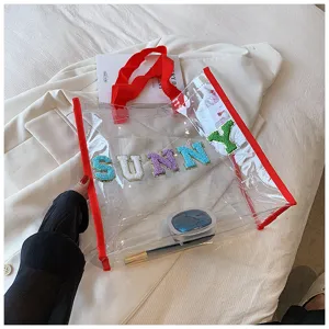 Transparente PVC Tragetasche Detailansicht mit bunten Sunny Bestickungsbuchstaben und rotem Rand.
