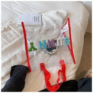 Transparente PVC Strandtasche Detailansicht mit bunten Buchstaben Patches und roten Riemen.