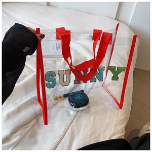 Transparente PVC Tragetasche Detailansicht, rote Riemen und funkelnde Buchstaben SUNNY Strandtasche.