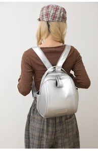 Silver shell backpack detail view showing stylish design, smooth metallic finish and straps.