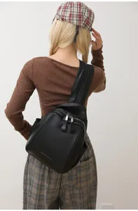 Black PU leather shell backpack detail shot showing multi-purpose casual design and metal zippers.