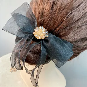 Zwarte organza haarstrik met champagne kristallen bloem en elegante lange linten.