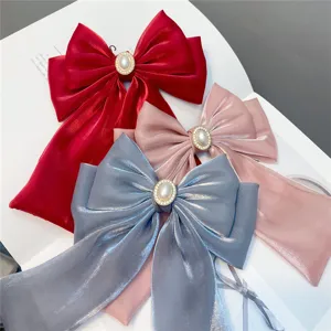 Detailed view of triple bow hair clip with pearl rhinestone and long ribbons, elegant design.