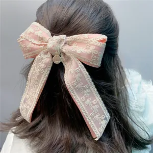 Detail view of pink lace bow hair clip, sweet hair accessory with metal pendant charm.