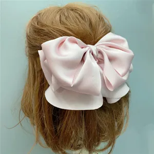 Pink satin hair bow clip detail closeup showcasing smooth fabric texture and elegant back view style.