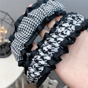 Detail view of black and white houndstooth fabric headband with ruffled edge for women winter.