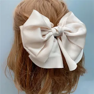 Elegant large satin hair bow detail close-up, classic vintage style hair clip for women.