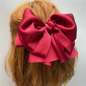 Detailed close-up of a large red satin bow hair clip, elegant vintage French style spring clip.
