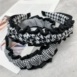 Closeup of black and white houndstooth headband with chic ruffled fabric edge and pleated design.