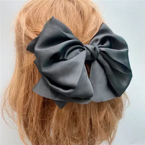 Detail view of a large black silk hair bow clip showing texture and back styling design.