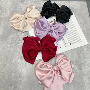 Detailed shot of multi-color satin large bow hair clips, elegant French vintage style.