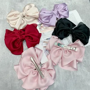 Detailed view of large satin bow hair clips in multiple colors, featuring sturdy metal spring clips.
