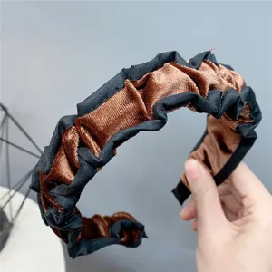 Detail view of the brown velvet and black ruffled pleated headband, showing texture.