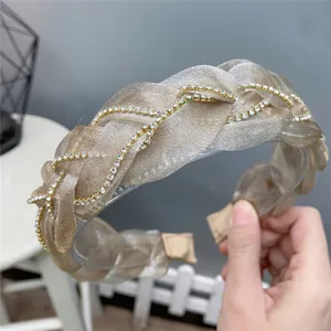 Detailed close-up of sparkling champagne organza braided headband decorated with rhinestones.