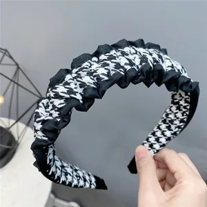 Close-up of a black and white houndstooth ruffle headband, stylish velvet hair hoop.