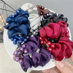 Detailed close-up of colorful satin hair scrunchies decorated with pearls and beads.