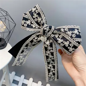 Detailed view of black double lace bow hair clip with pearl pendant, elegant hair accessory.