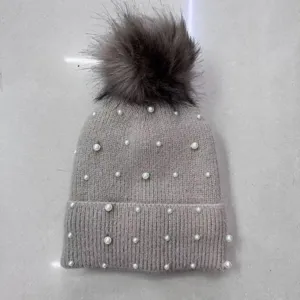 Close-up detail of grey winter knit beanie decorated with elegant pearls and fluffy pom-pom.