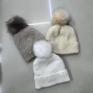 Detailed close-up view of cozy knitted winter beanies featuring elegant pearls and soft pom-poms.