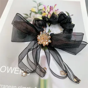 Zwarte organza haarscrunchie met kristallen bloemstrik en lange bungelende linten.