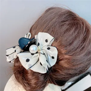 Detailed close-up of a sweet black and white polka dot bow hair claw clip with pearl.