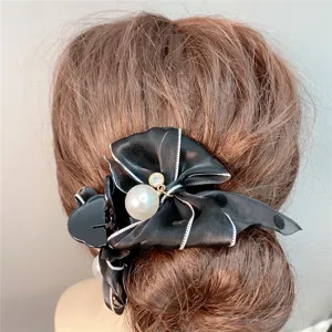 Close-up detail of the elegant black polka dot bow hair claw clip with pearl and rhinestone.