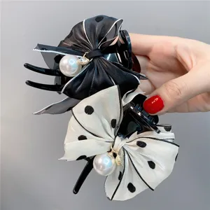 Close-up detail of sweet bow hair claw clip with elegant pearls and chic polka dot pattern.