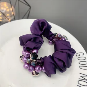 Purple fabric hair scrunchie with pearl beads and floral charm, elegant accessory for women.